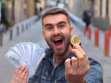 Mladý muž nadšeně drží bitcoinovou minci a hotovost, symbolizující rychlé zbohatnutí na kryptoměnách a příběhy některých raných investorů.