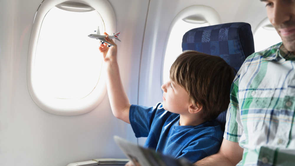 Boy on a plane holding a miniature plane in his hand.