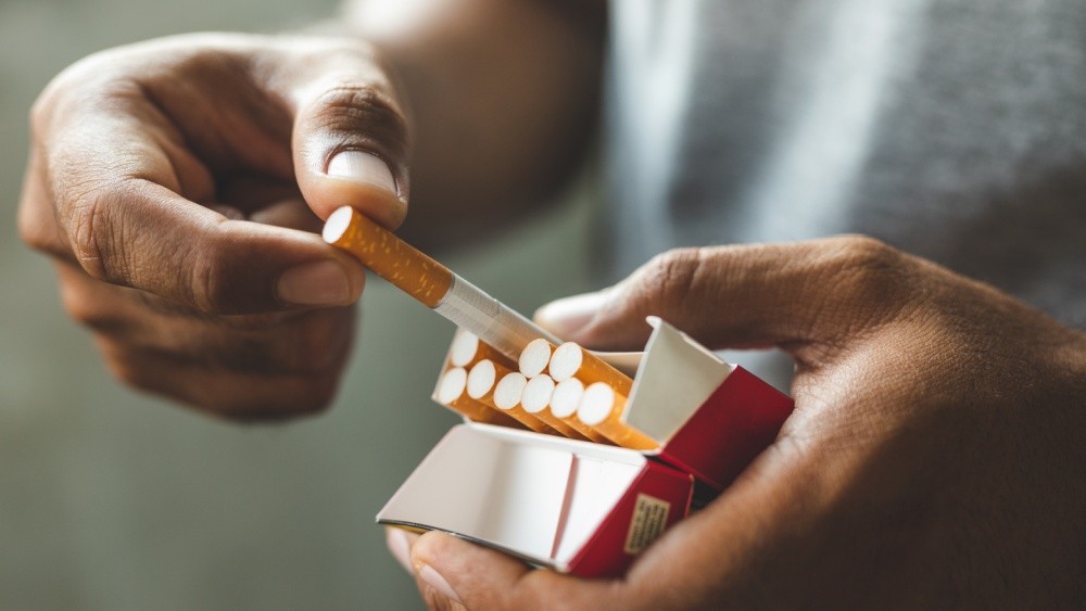 person taking a cigarette out of a package.