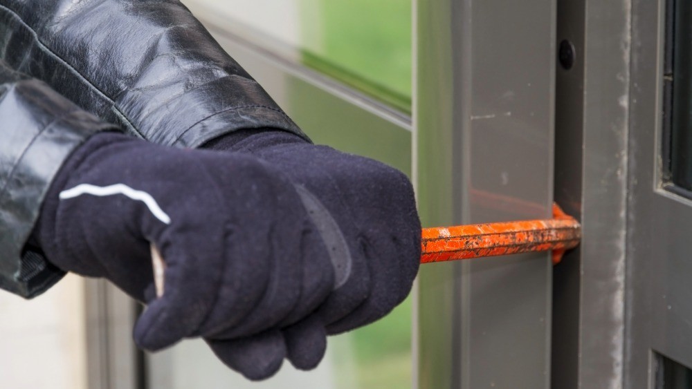 person wearing gloves and forcing a door to open