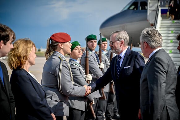 Premi�r Petr Fiala se na leti�ti v Berl�n� zdrav� s �lenkou uv�tac� delegace, 22. �ervence 2025.