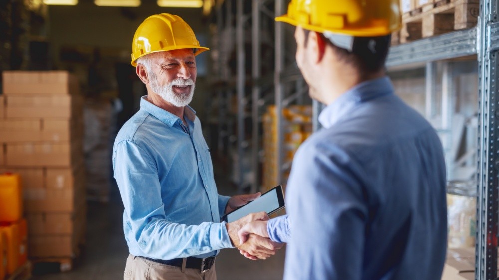 two men wearing yellow helmets and hand shaking