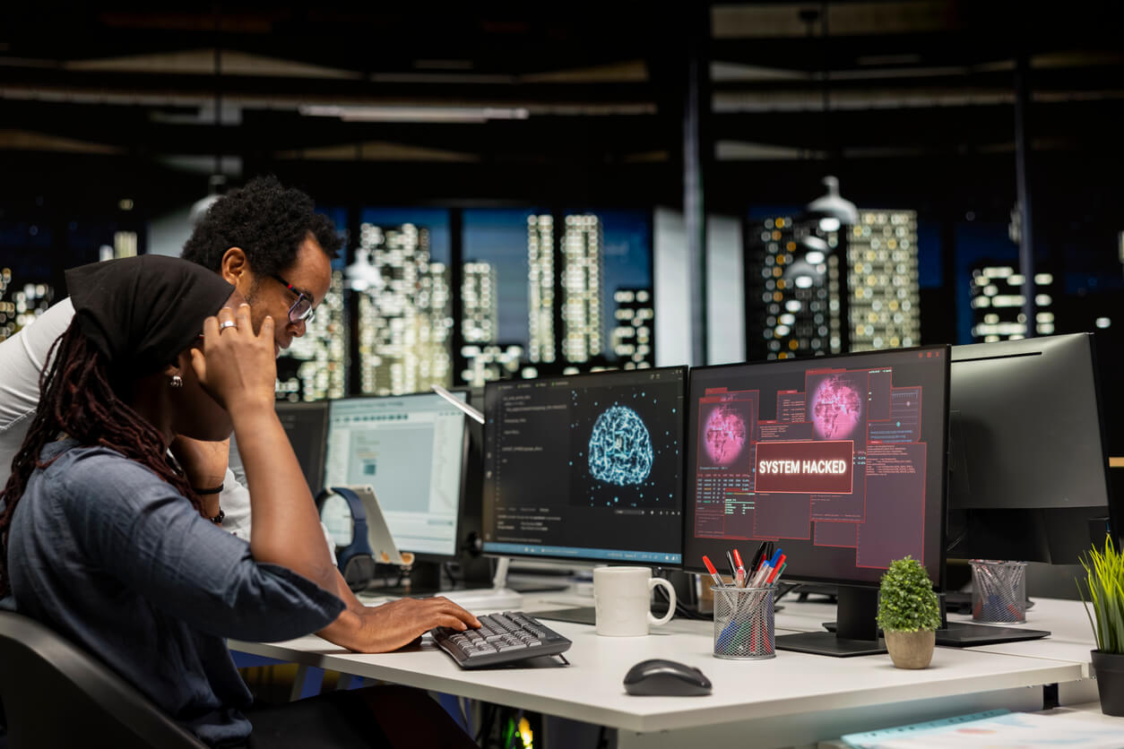 Young female programmer in office requests help from manager to block hacker