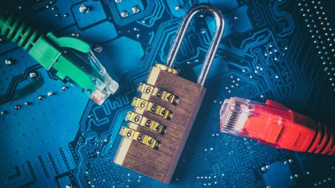 A blue circuit board with a brass padlock and two Ethernet cables, one green and one red, connected to it.