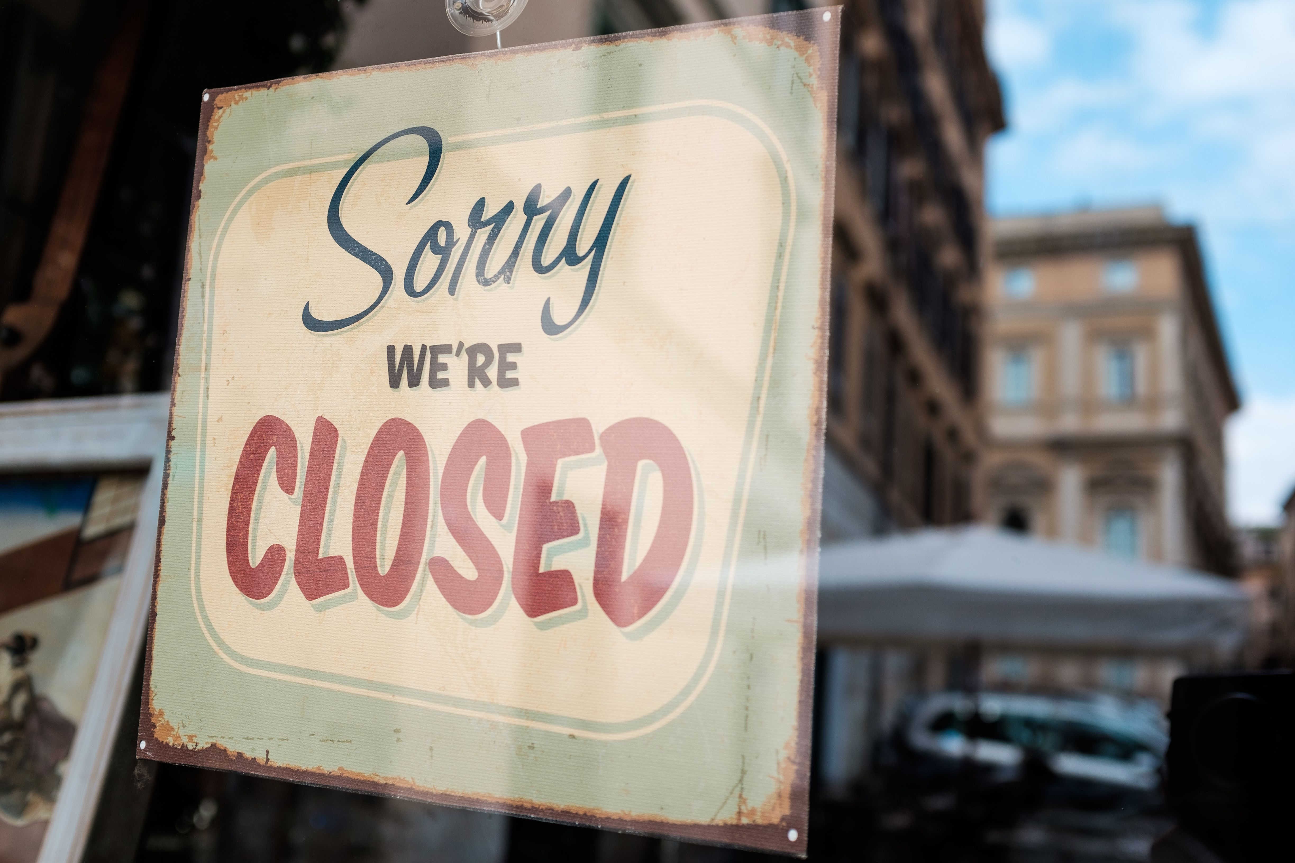 A business with a sign on the door that reads 'closed'.