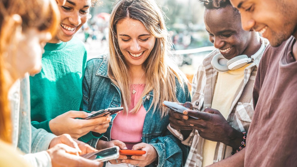 group of young people smilling and looking at their phones