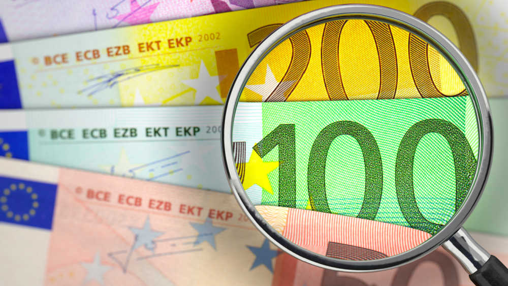 euro bank notes underneath a magnifying glass