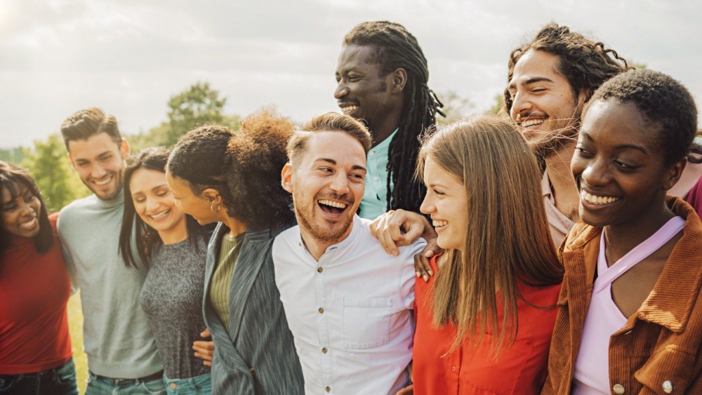 A group of diverse young people hugging and laughing.