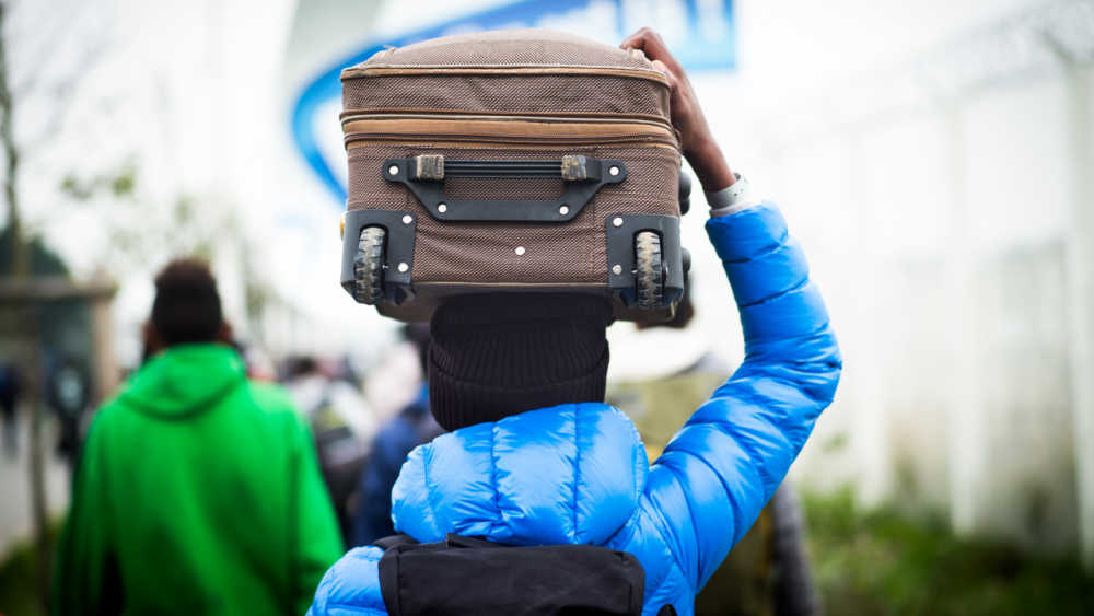 An adult carrying a suitcase.