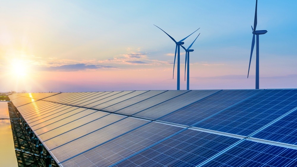 Solar panels with wind turbines in the background.